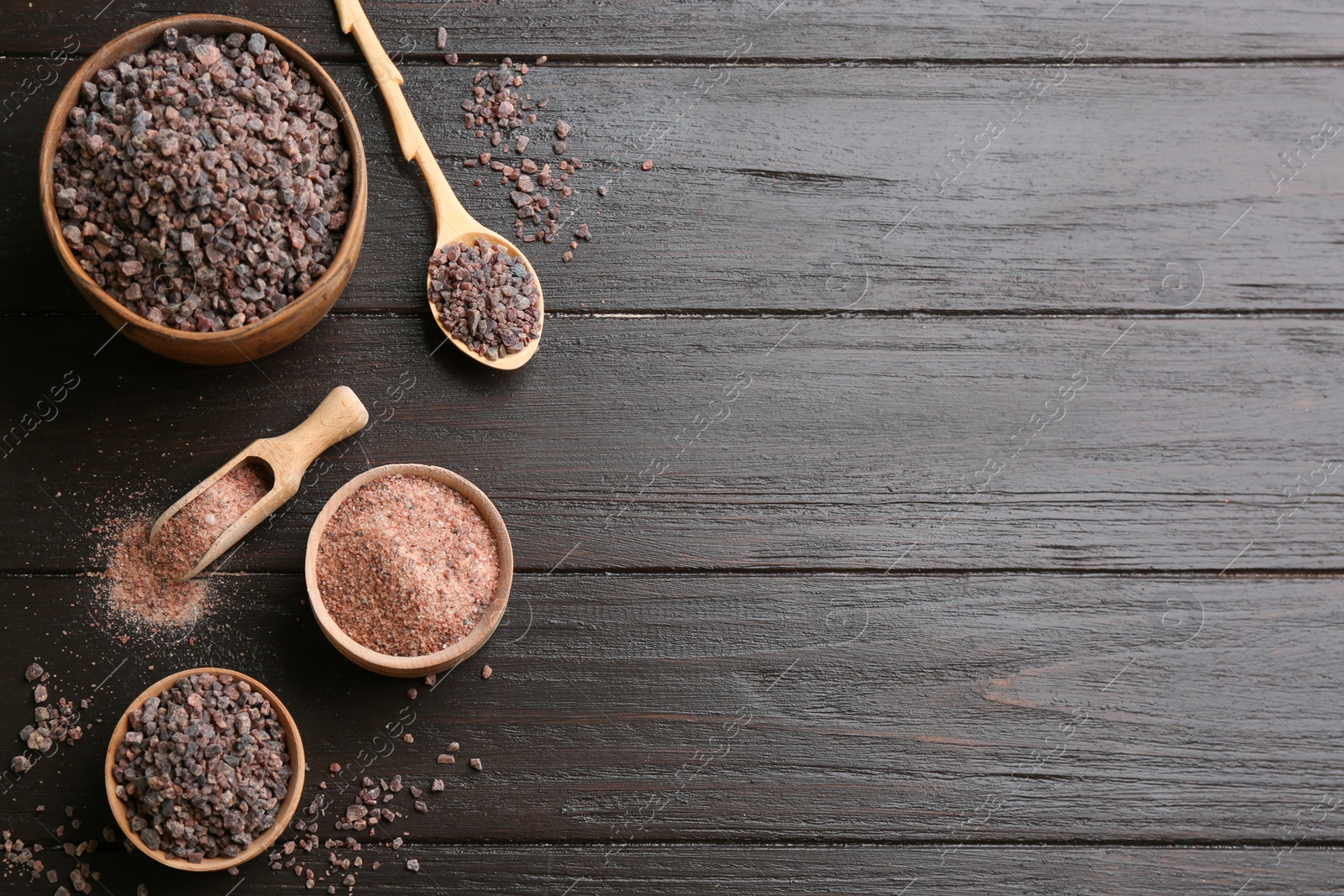 Photo of Black salt on wooden table, flat lay. Space for text