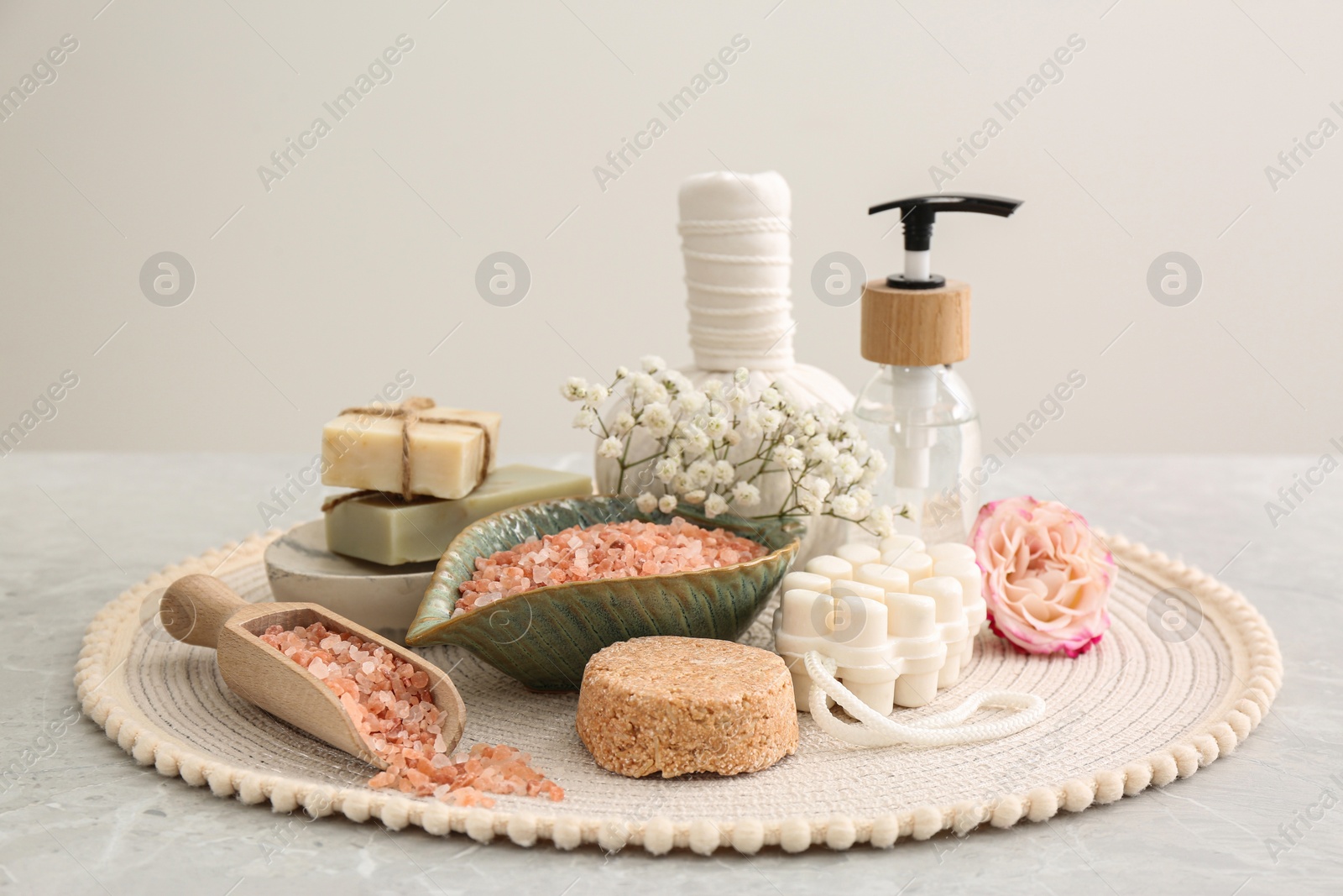 Photo of Sea salt and different spa products on light grey marble table