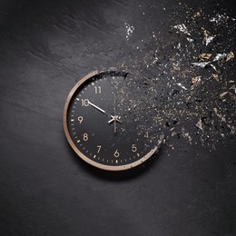 Image of Fleeting time concept. Analog clock dissolving on black background