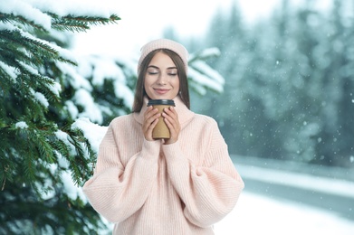 Image of Happy beautiful woman with mulled wine outdoors on snowy day 