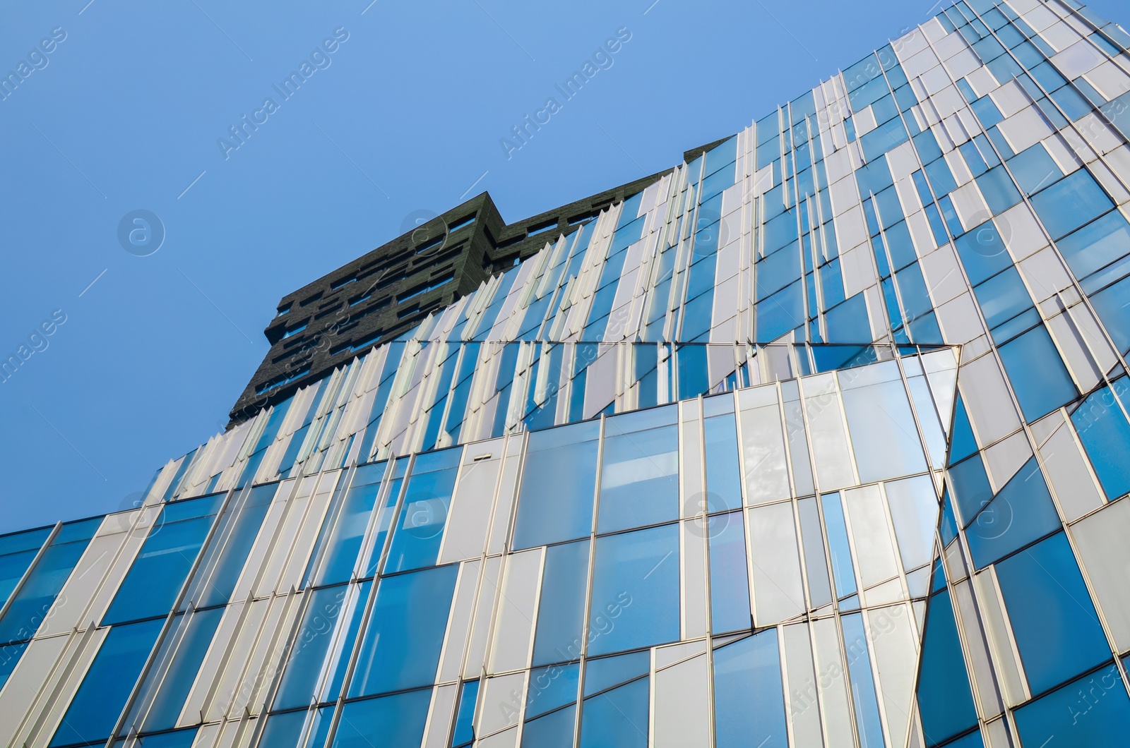 Photo of Exterior of beautiful modern skyscraper against blue sky, low angle view