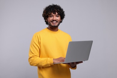 Smiling man with laptop on light grey background