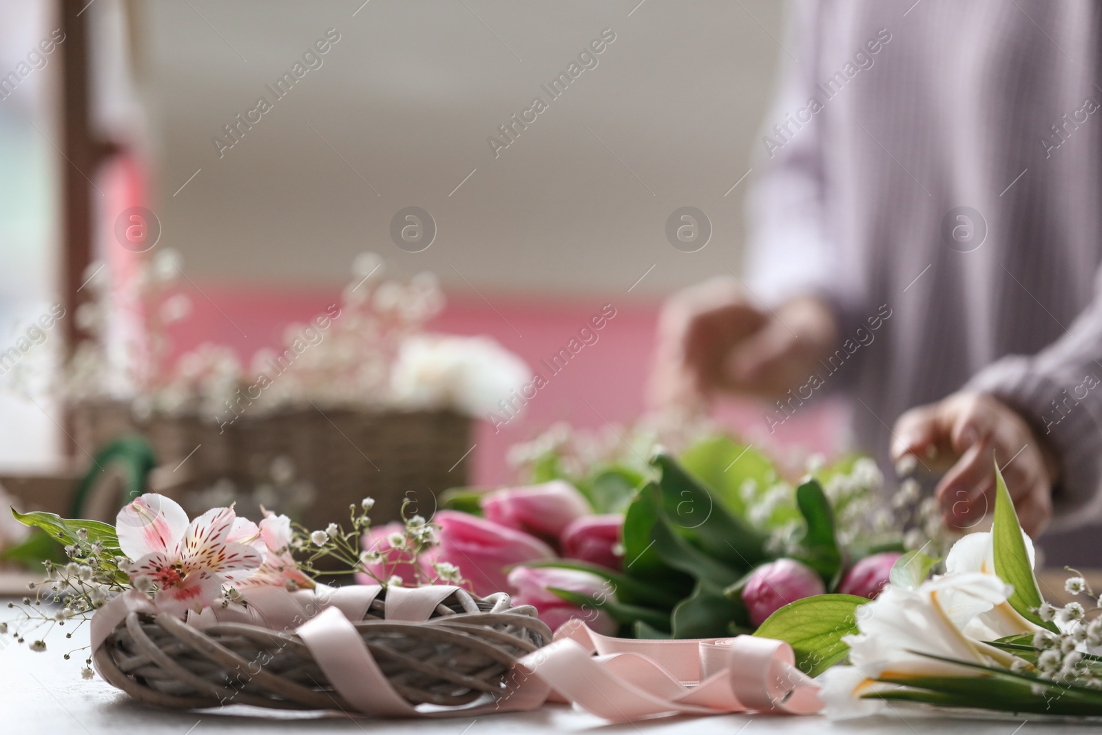 Photo of Decorator's workplace with unfinished wreath and blurred woman on background