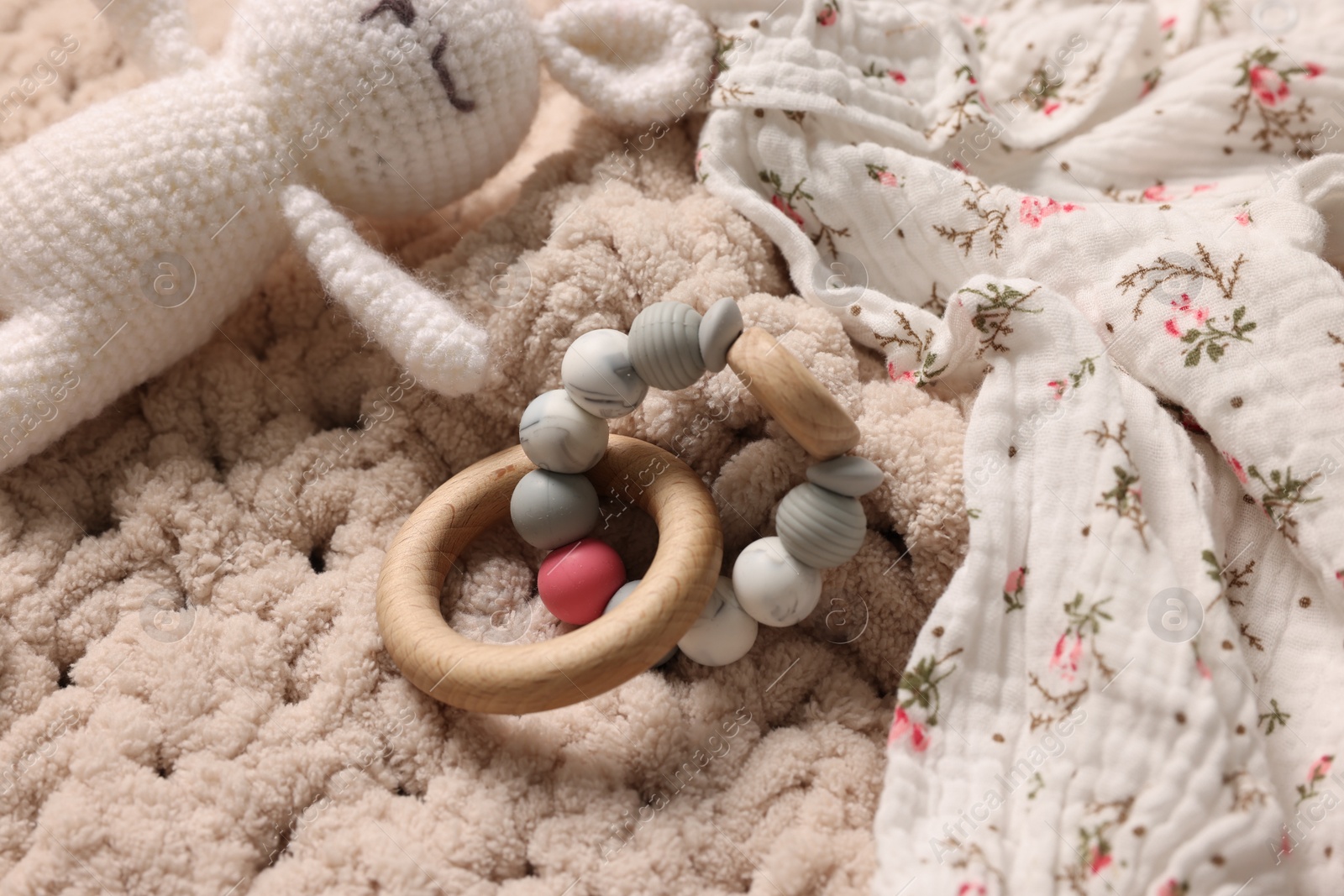 Photo of Baby accessories. Toys and cloth on knitted fabric, closeup