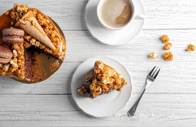 Photo of Delicious homemade cake with caramel sauce and cup of coffee on table, top view