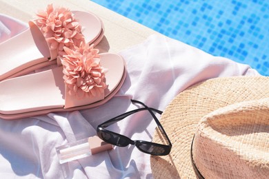 Photo of Pink blanket with beach accessories near outdoor swimming pool on sunny day, above view