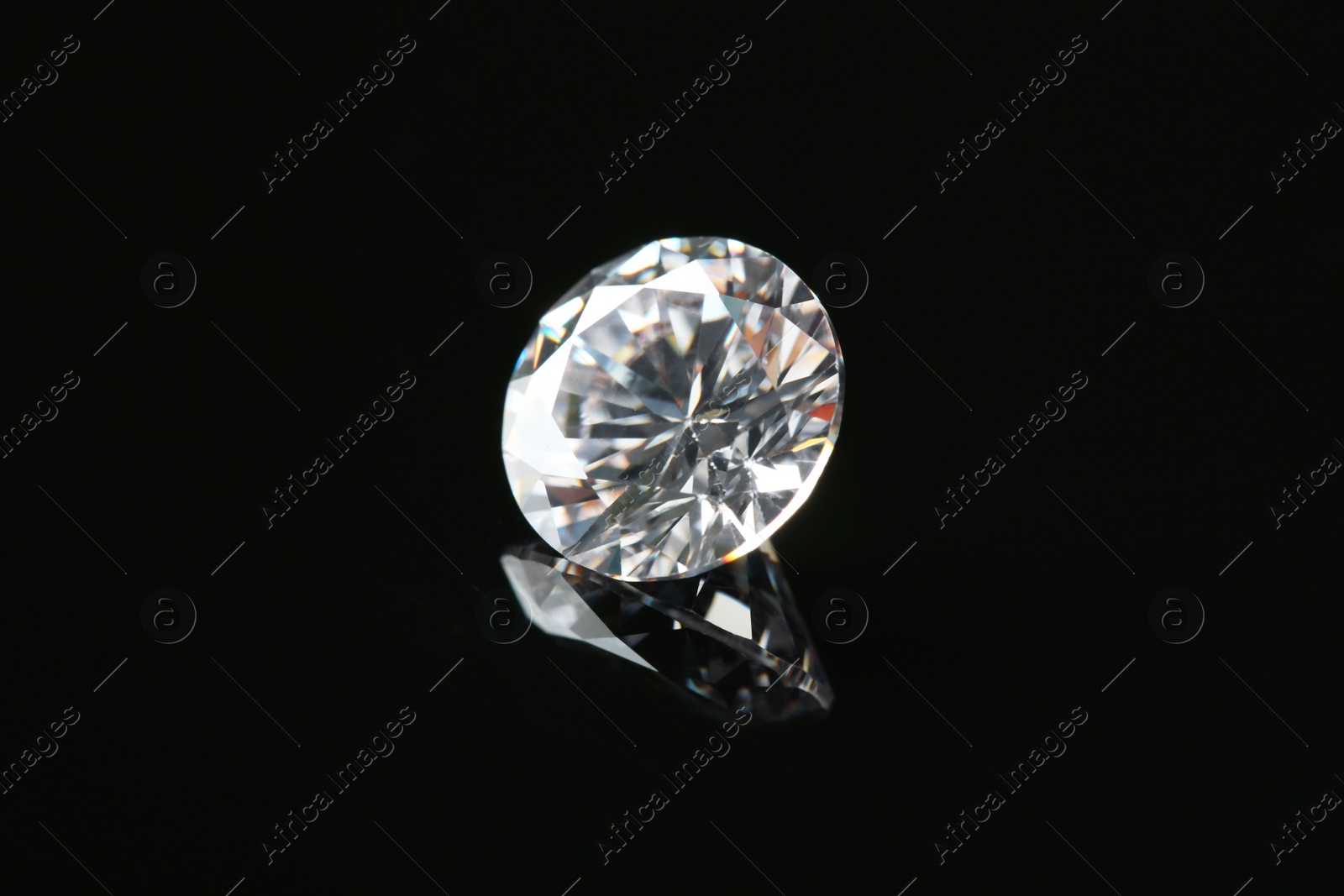 Photo of Beautiful shiny diamond on black mirror surface