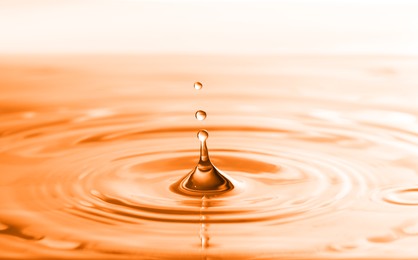Image of Splash of water with drops as background, closeup. Toned in orange