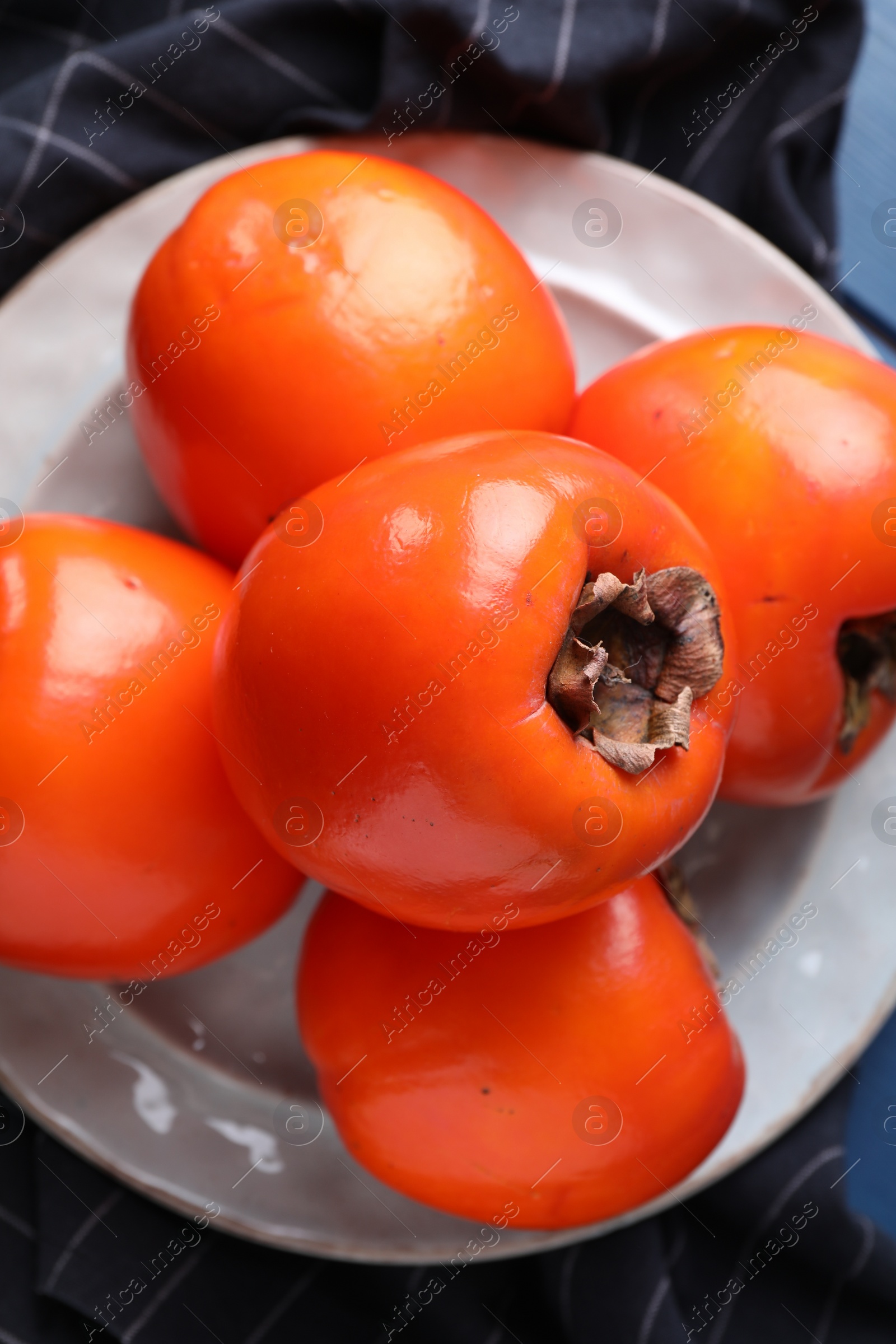 Photo of Delicious ripe persimmons and plate on table, top view