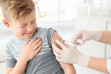 Photo of Doctor vaccinating little boy in hospital