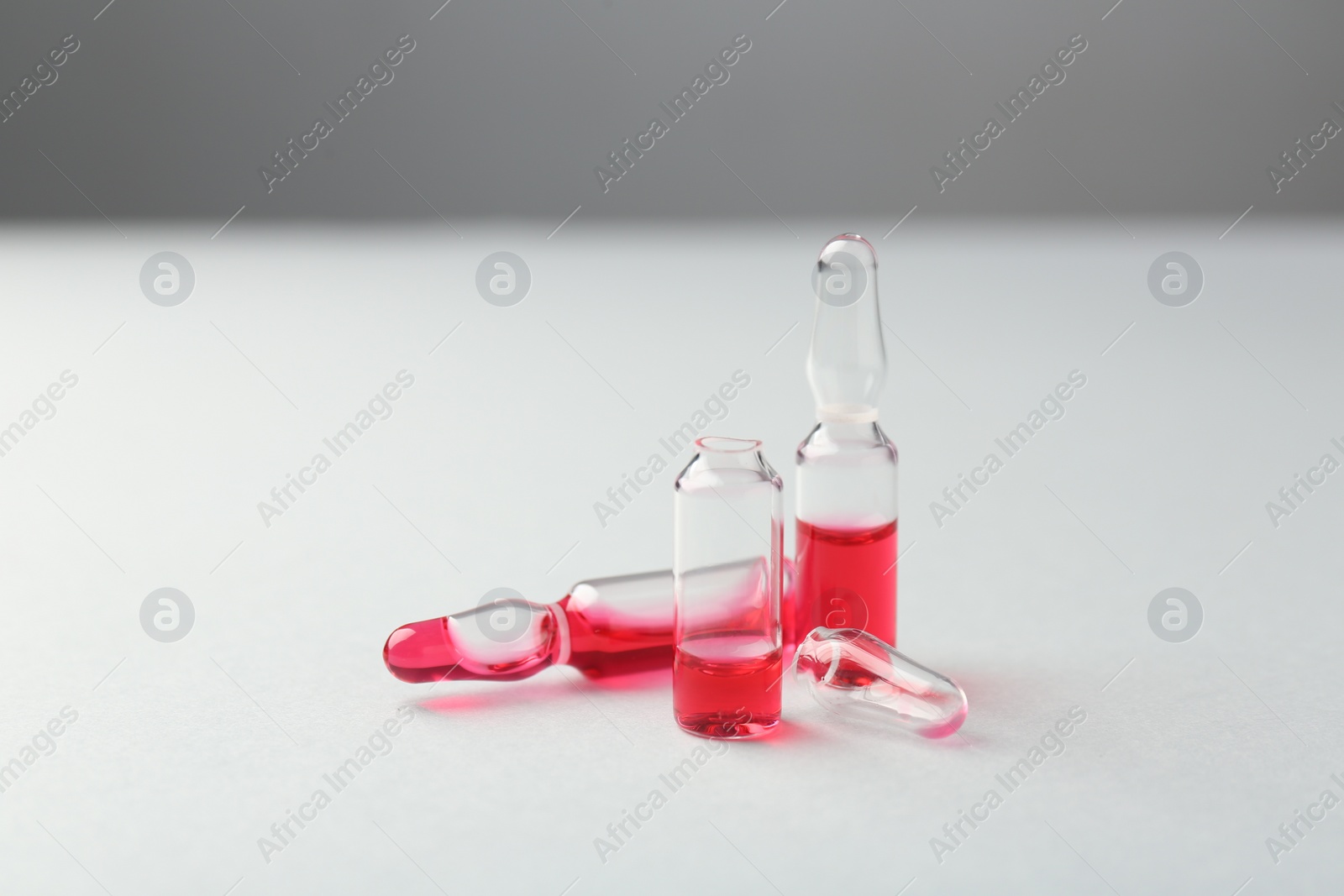 Photo of Glass ampoules with liquid on white background