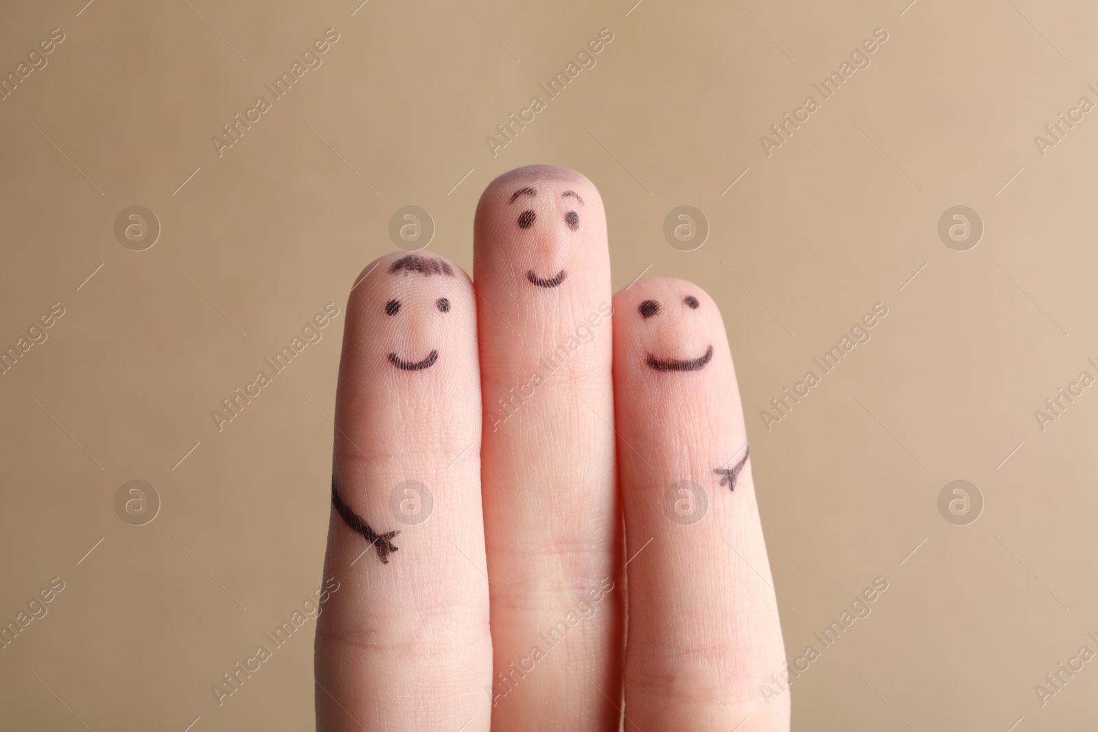 Photo of Three fingers with drawings of happy faces on brown background