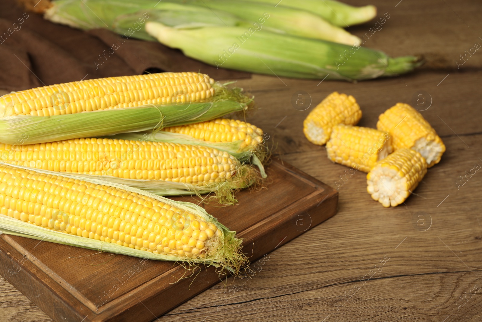 Photo of Tasty sweet corn cobs on wooden table