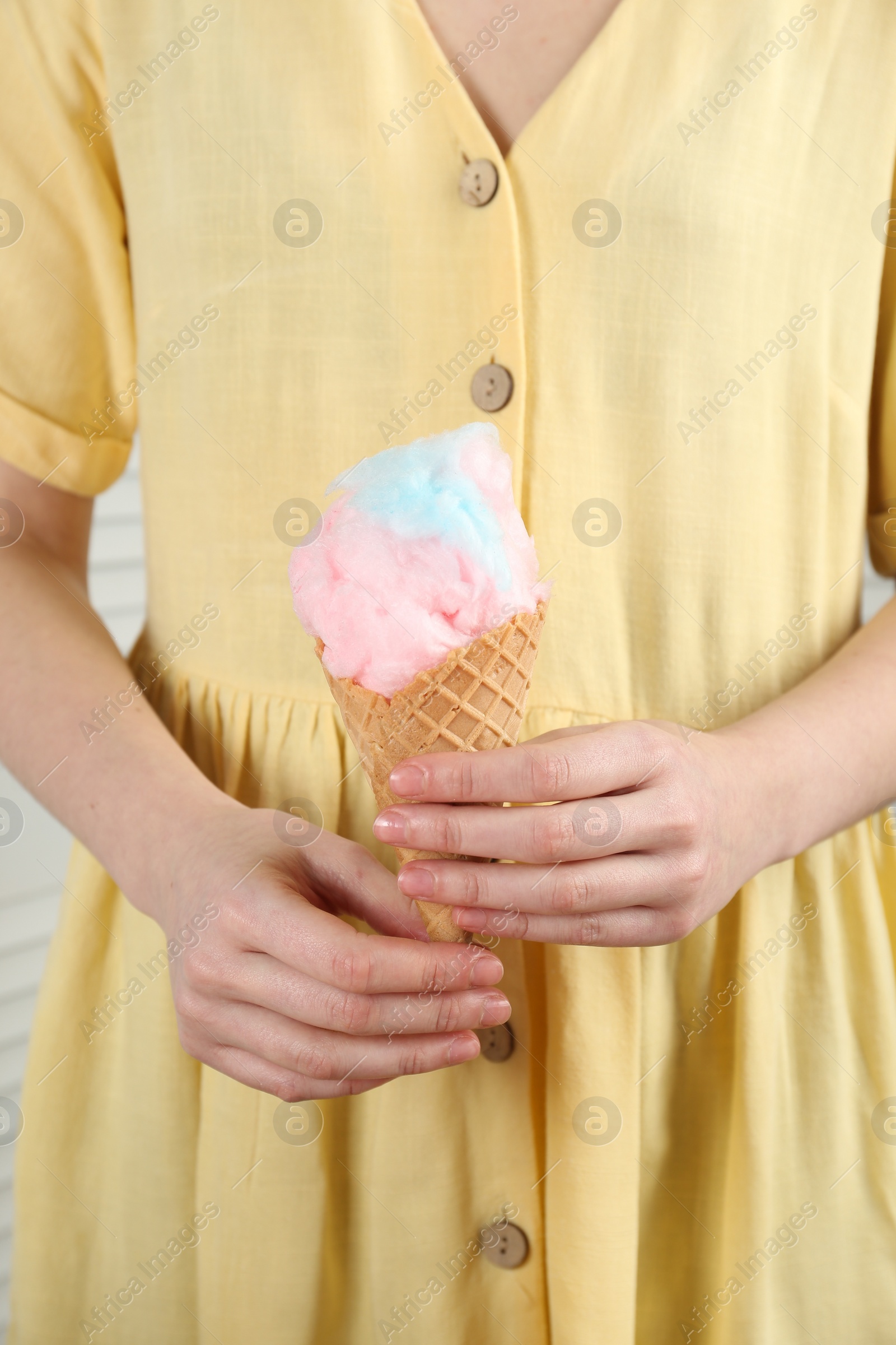 Photo of Woman holding waffle cone with cotton candy, closeup