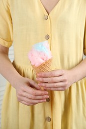 Photo of Woman holding waffle cone with cotton candy, closeup