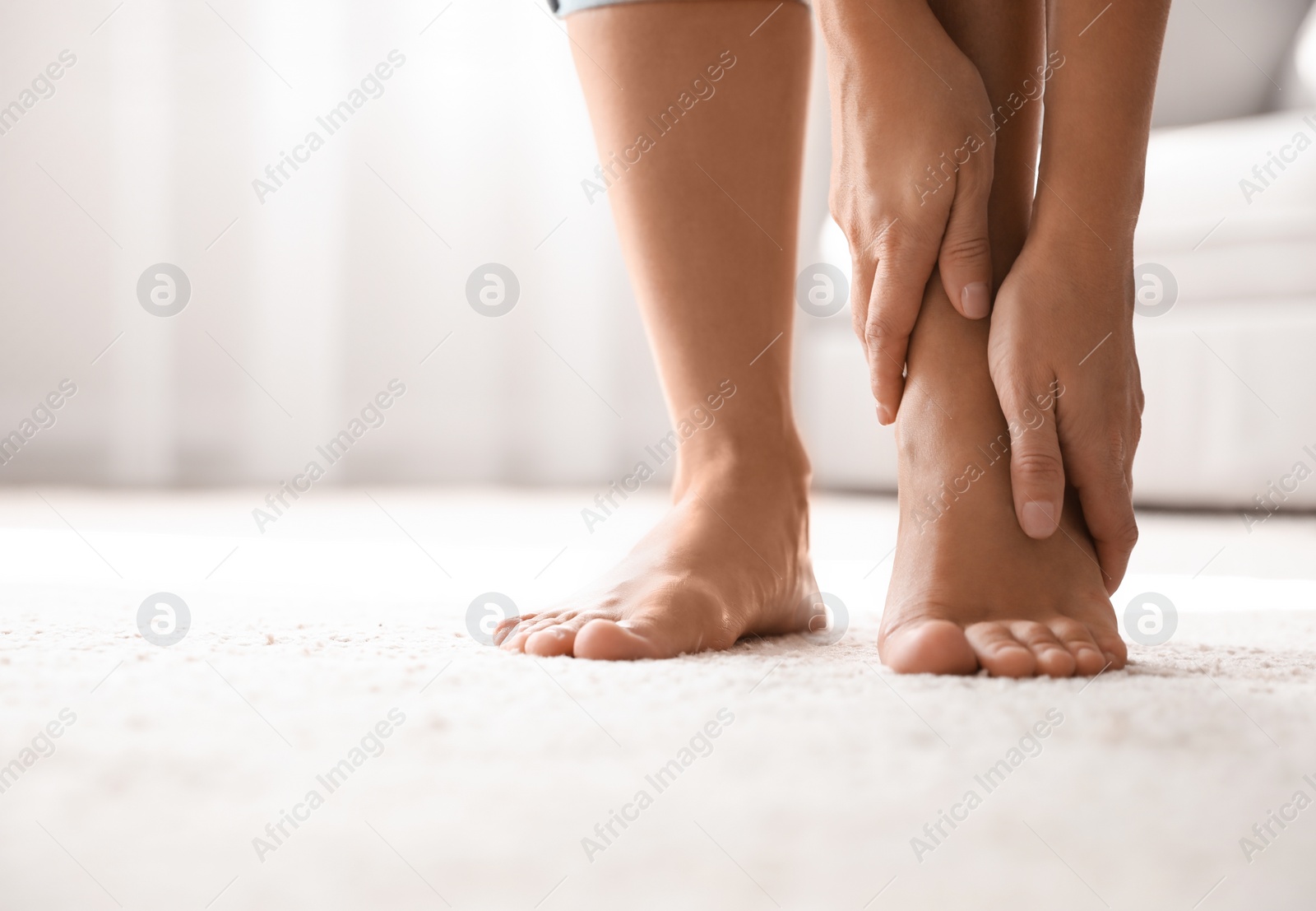 Photo of Young woman suffering from pain in foot indoors, closeup