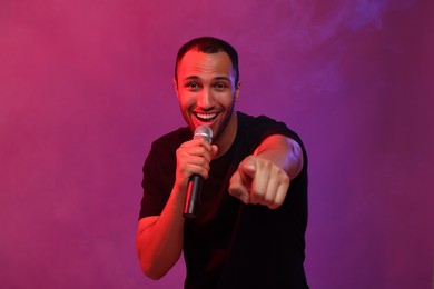 Photo of Handsome man with microphone singing on pink background. Color tone effect