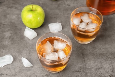 Glasses of apple juice with ice cubes on table