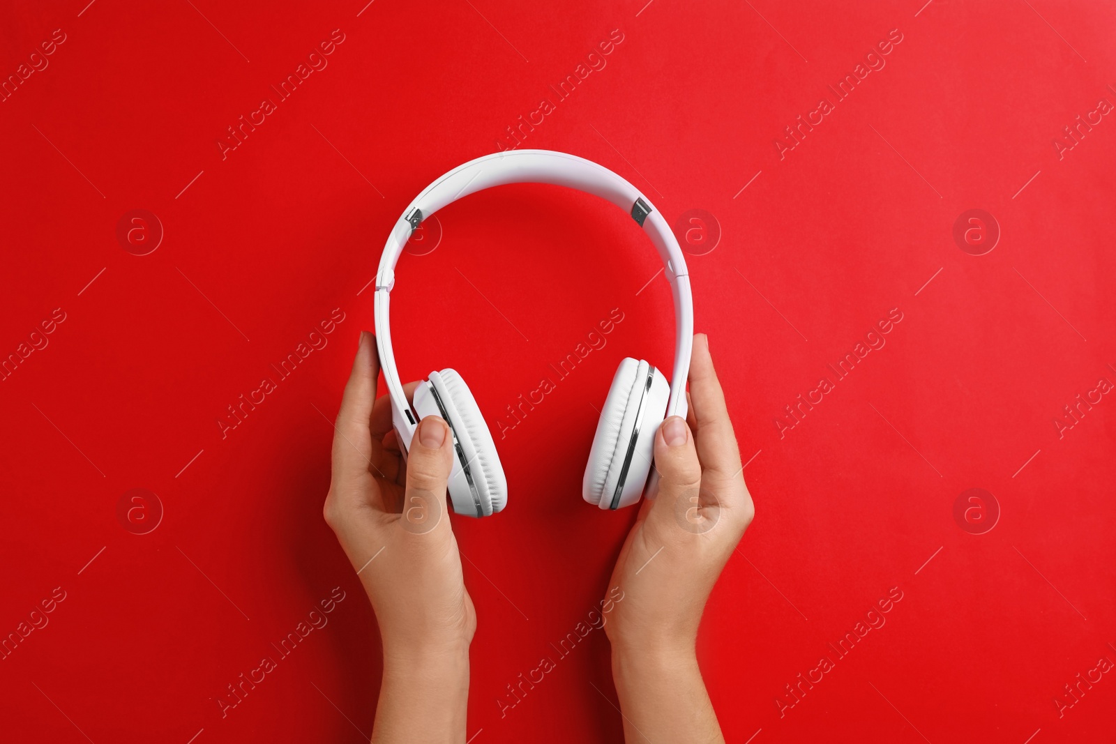 Photo of Woman holding headphones on color background, top view