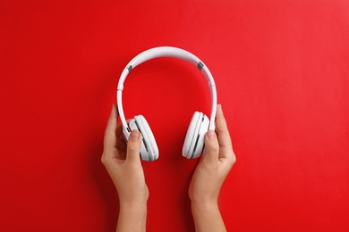 Woman holding headphones on color background, top view