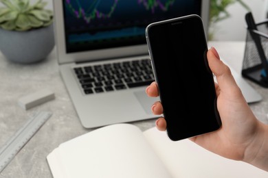 Woman holding smartphone indoors, closeup. Space for text