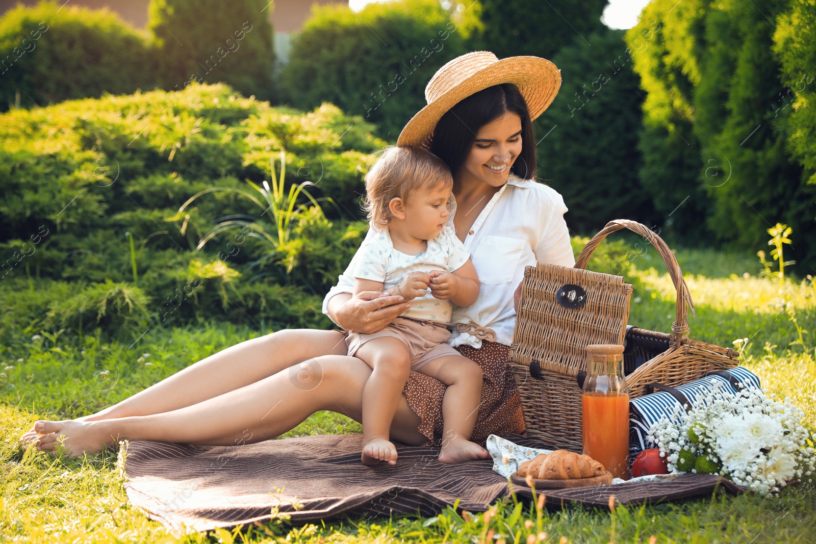 Photo of Mother with her baby daughter having picnic in garden on sunny day