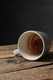 Poverty. Overturned dirty cup and coins on wooden table