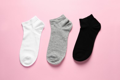 Photo of Different socks on pink background, flat lay