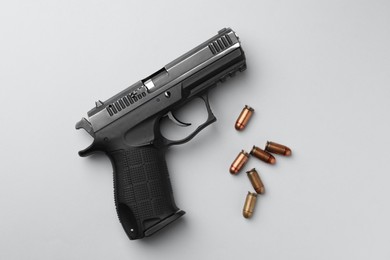 Semi-automatic pistol and bullets on light background, flat lay