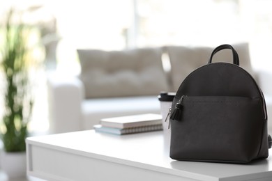 Stylish black backpack on white table indoors, space for text