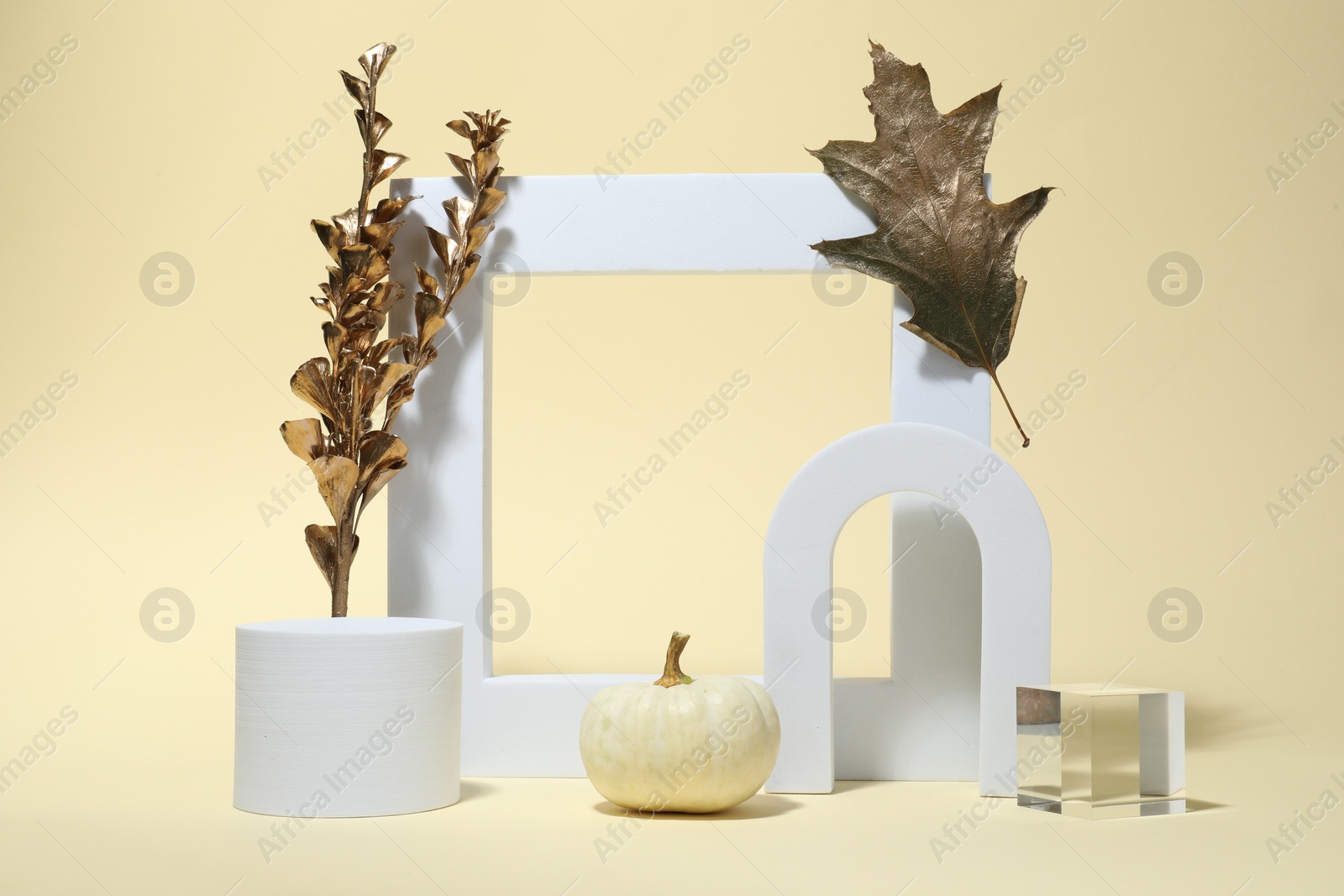 Photo of Autumn presentation for product. Geometric figures, golden branch with leaves and pumpkin on beige background