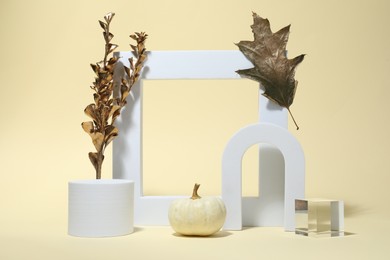 Photo of Autumn presentation for product. Geometric figures, golden branch with leaves and pumpkin on beige background