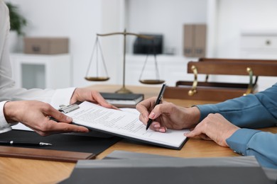 Senior woman signing document in lawyer's office, closeup