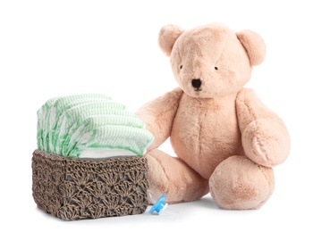 Photo of Basket with diapers, pacifier and teddy bear on white background. Baby accessories