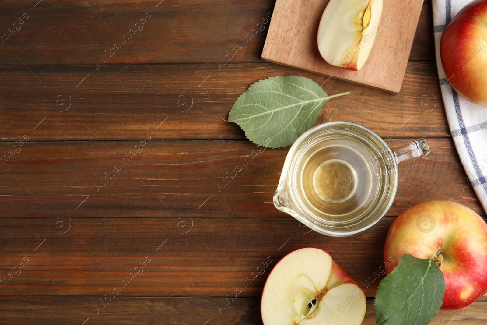 Photo of Natural apple vinegar and fresh fruits on wooden table, flat lay. Space for text