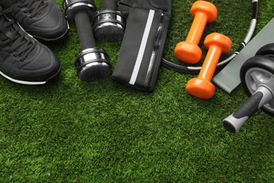 Photo of Different sports equipment on green grass, above view. Space for text