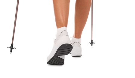 Woman wearing stylish shoes with trekking poles on white background, closeup