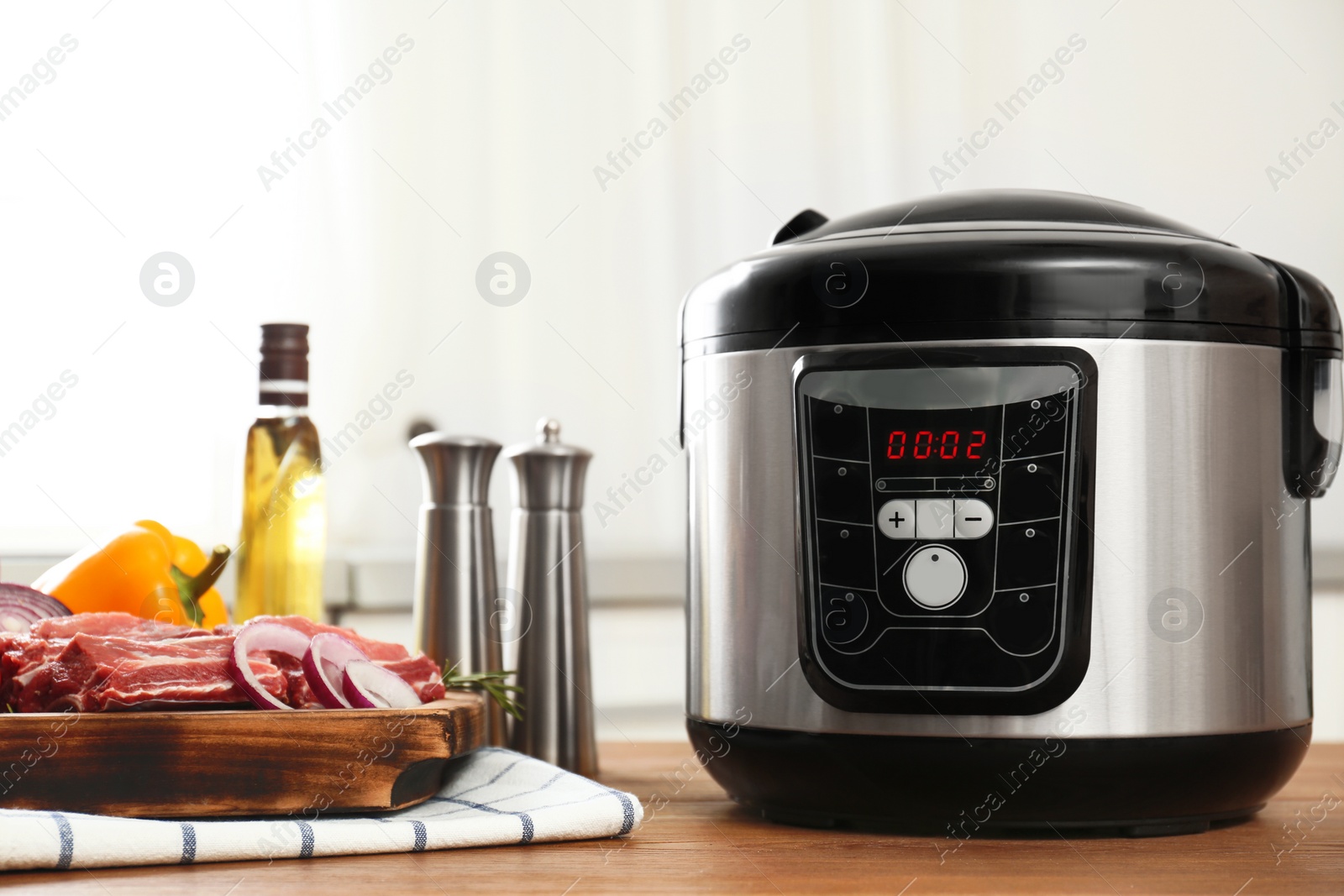 Photo of Modern multi cooker and products on wooden table in kitchen