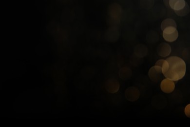 Photo of Blurred view of golden lights on black background, space for text. Bokeh effect