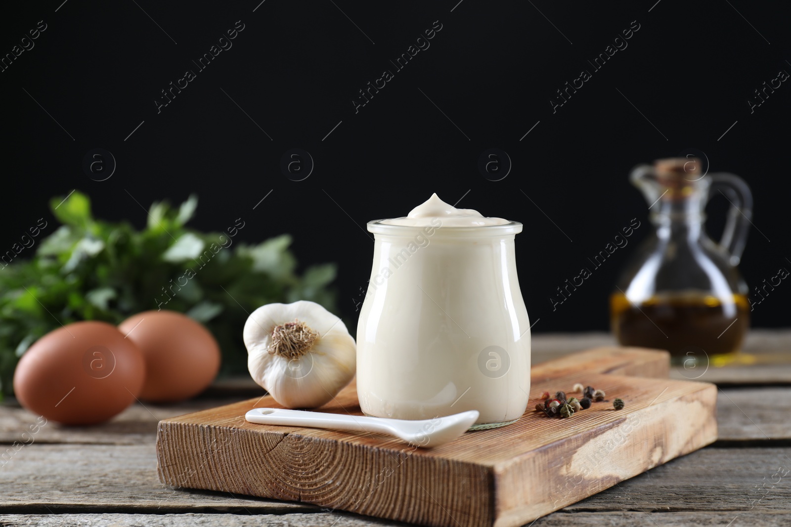 Photo of Fresh mayonnaise sauce in glass jar and ingredients on wooden table