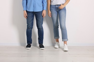 People in stylish jeans near white wall indoors, closeup