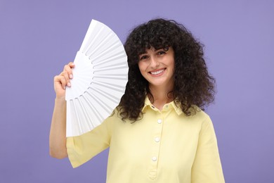 Photo of Happy woman holding hand fan on purple background