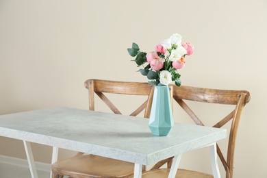 Vase with beautiful flowers as element of interior design on table in room. Space for text