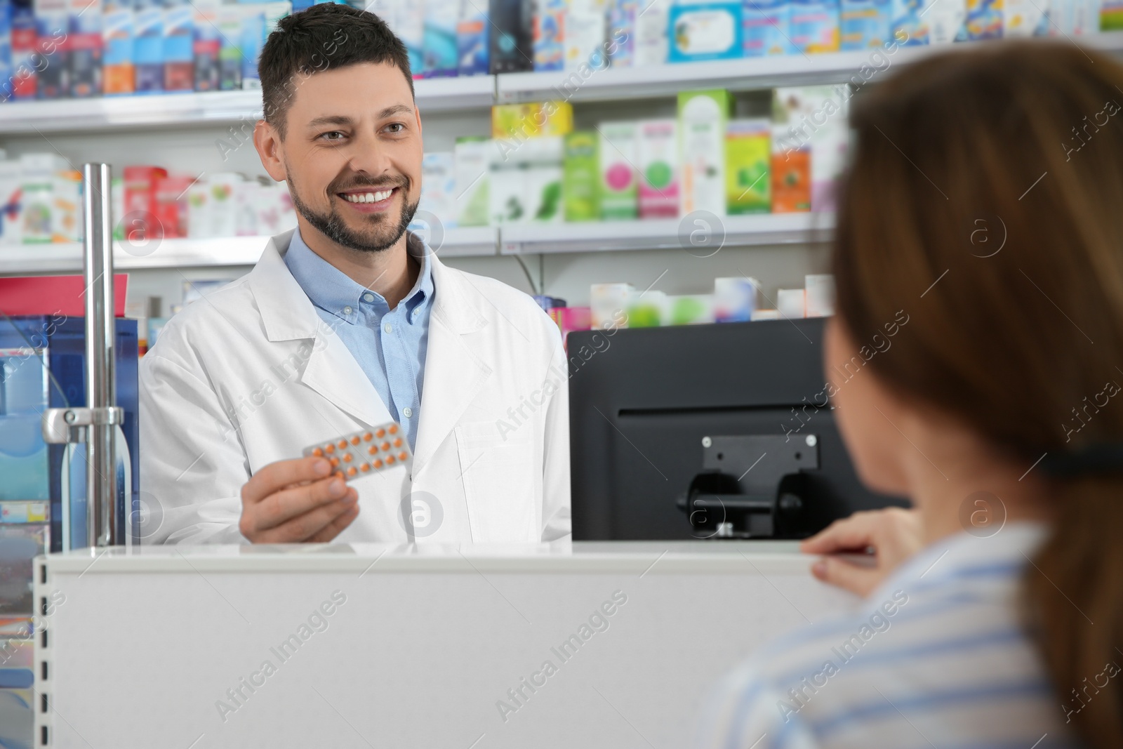 Photo of Professional pharmacist giving pills to customer in drugstore