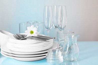 Set of clean dishes, glasses and cutlery on light blue table