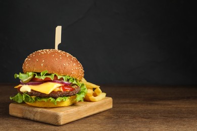 Photo of Delicious burger with beef patty and french fries on wooden table, space for text