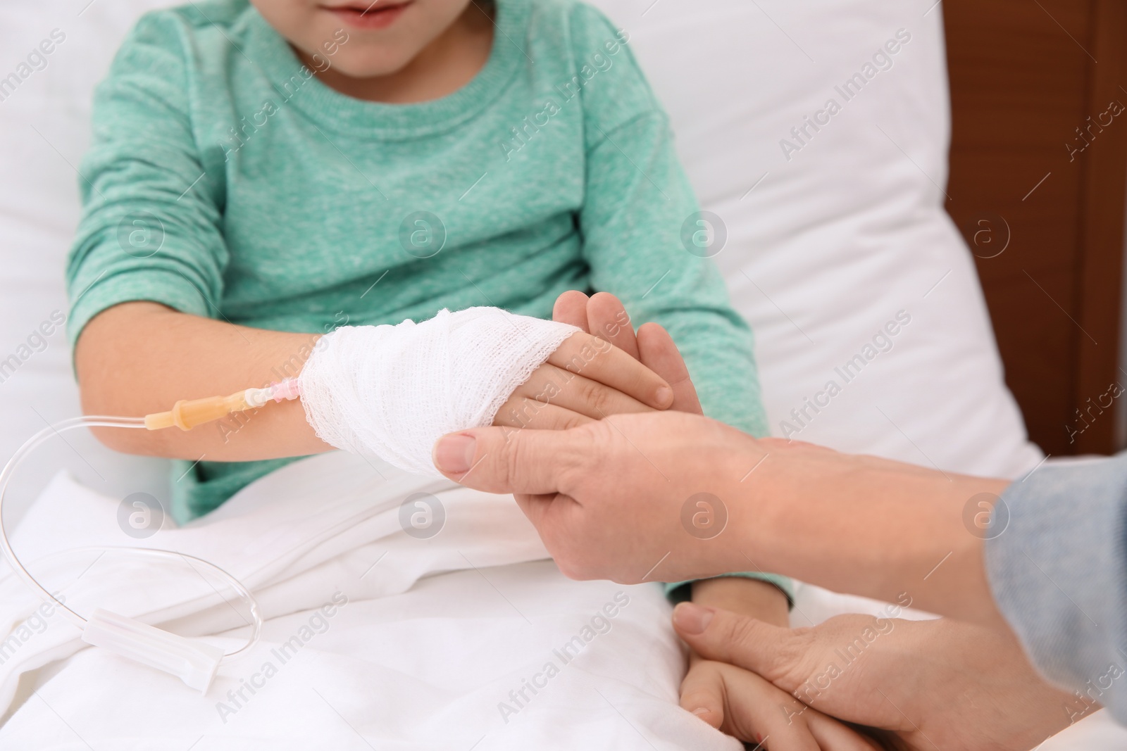 Photo of Woman visiting her little child with intravenous drip in hospital, closeup