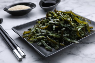 Photo of Fresh laminaria (kelp) seaweed served on white marble table, closeup