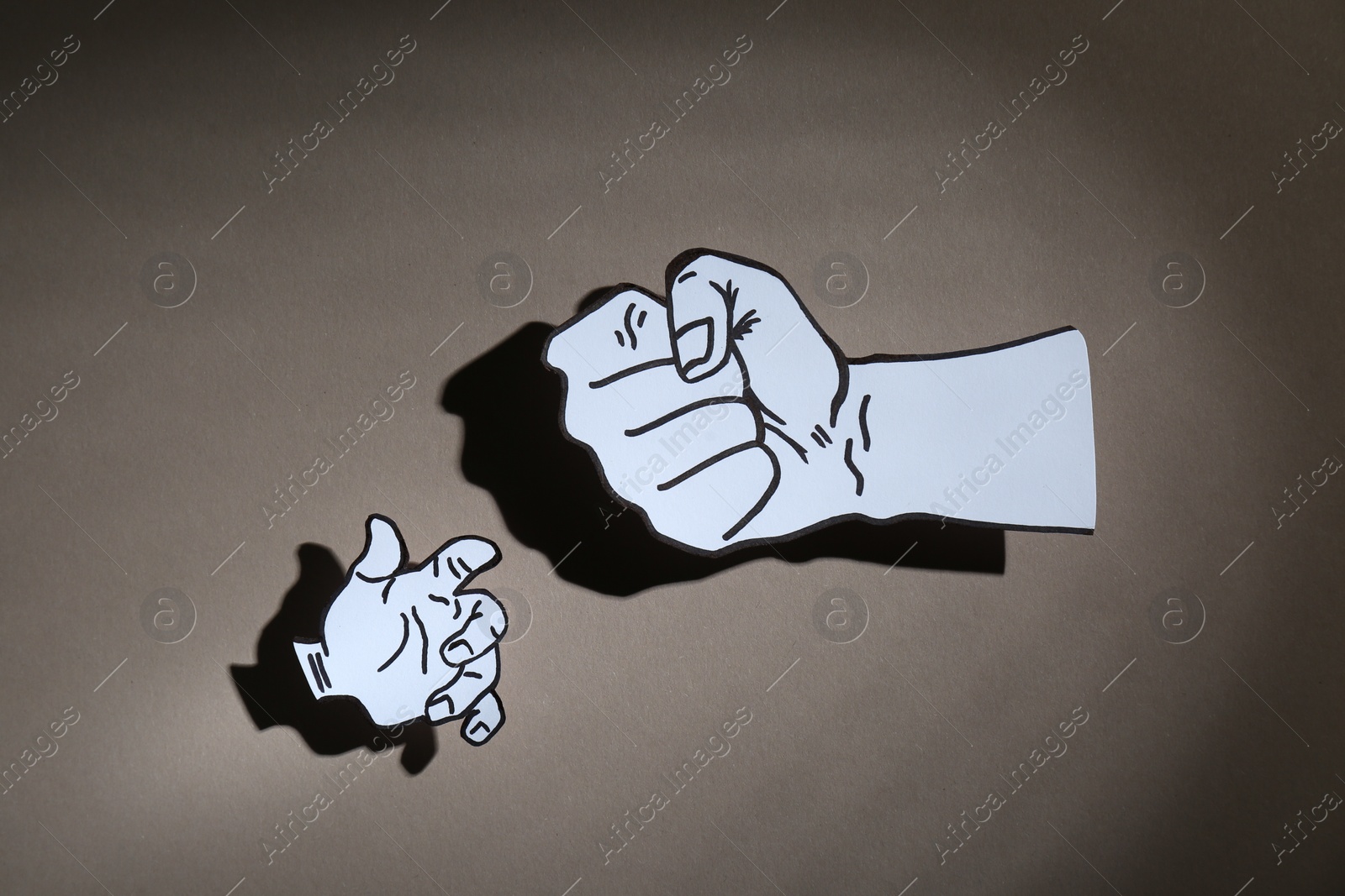 Photo of Stop child abuse. Paper cutout in shape of parent's fist above kid's hand on grey background, top view