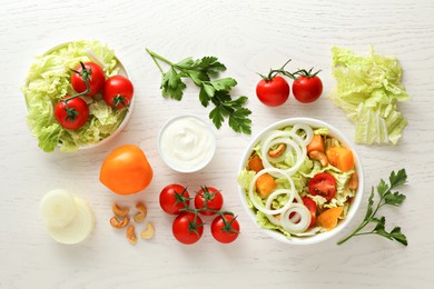 Photo of Bowl of delicious salad with Chinese cabbage and different ingredients on white wooden table, flat lay